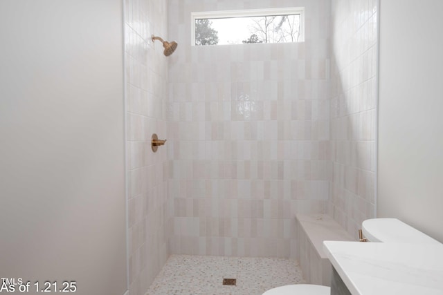 full bathroom featuring vanity, a tile shower, and toilet