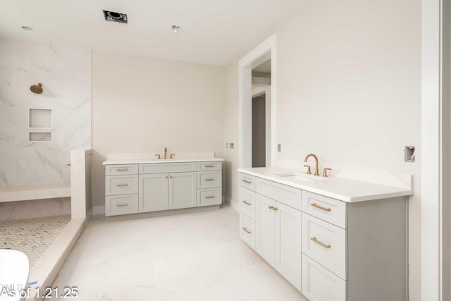 full bathroom featuring two vanities, a sink, and a marble finish shower