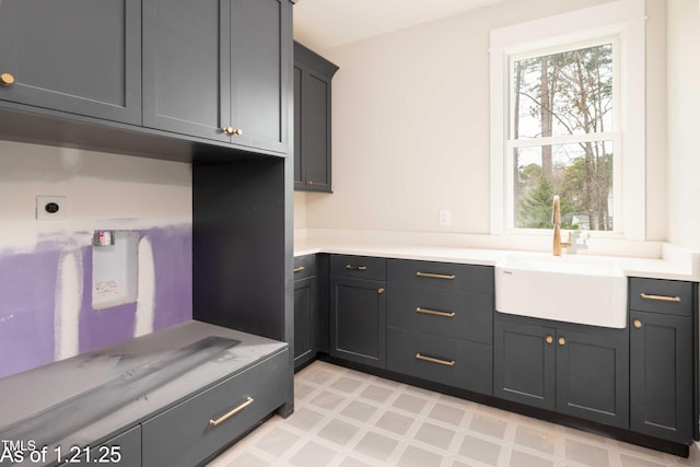 laundry area with cabinet space, a sink, electric dryer hookup, and light floors