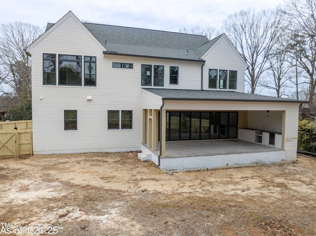 back of house featuring an attached garage, a patio area, and a shingled roof