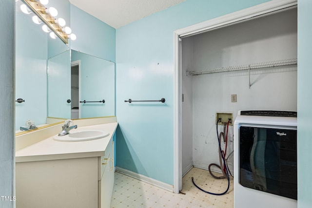 bathroom featuring a textured ceiling, washer / dryer, and vanity