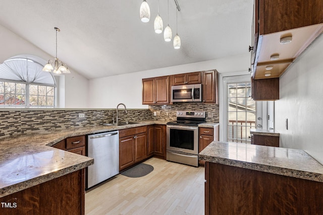 kitchen featuring lofted ceiling, tasteful backsplash, pendant lighting, sink, and appliances with stainless steel finishes