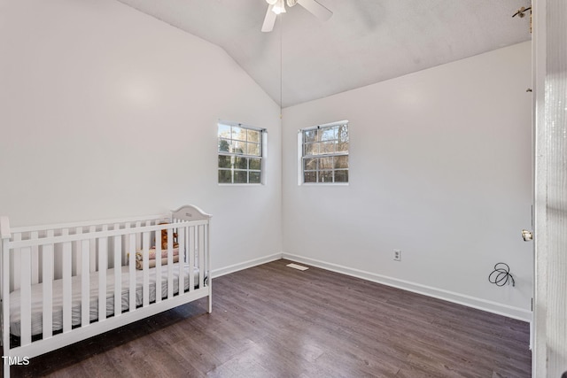 unfurnished bedroom featuring ceiling fan, a nursery area, dark wood-type flooring, and lofted ceiling