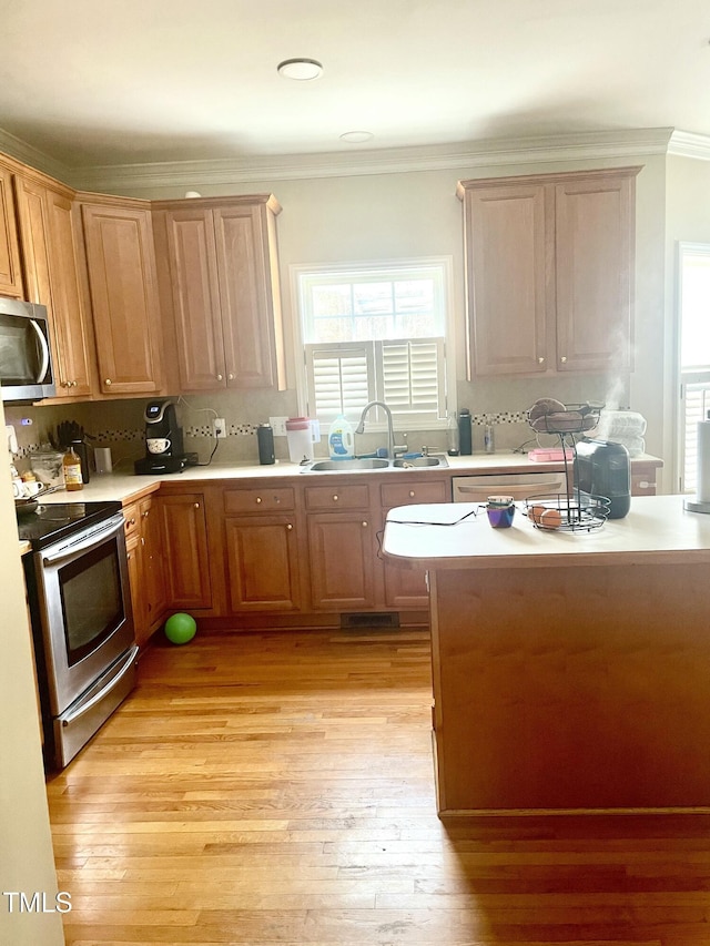 kitchen with sink, crown molding, light hardwood / wood-style flooring, appliances with stainless steel finishes, and decorative backsplash