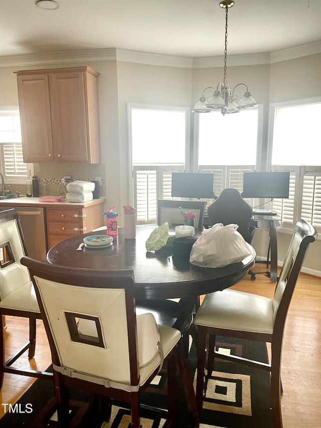 dining space featuring sink, light hardwood / wood-style flooring, ornamental molding, and a chandelier