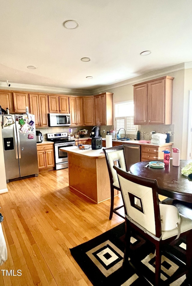 kitchen with sink, crown molding, stainless steel appliances, light hardwood / wood-style floors, and decorative backsplash