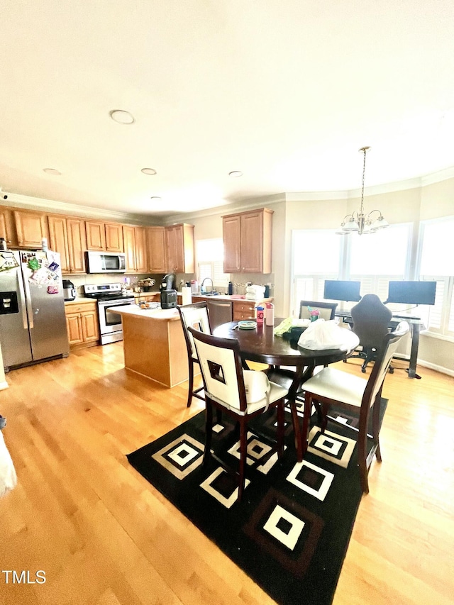 dining area featuring crown molding, an inviting chandelier, sink, and light hardwood / wood-style floors