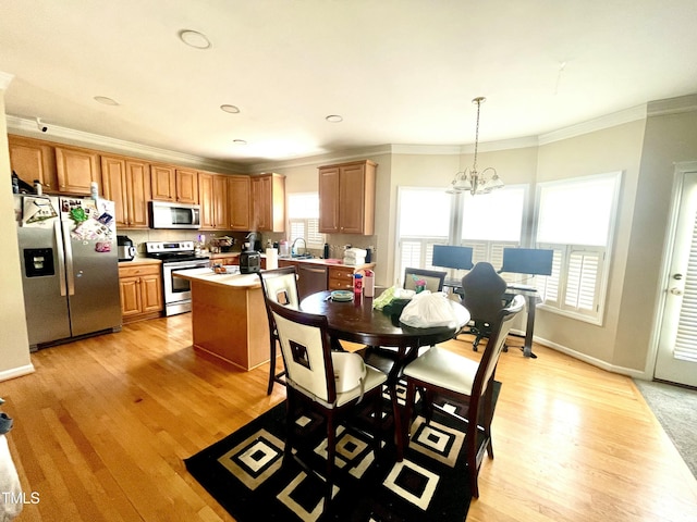 dining room featuring crown molding, sink, an inviting chandelier, and light hardwood / wood-style floors