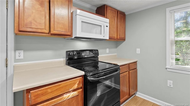 kitchen featuring ornamental molding, built in desk, light wood-type flooring, and black / electric stove