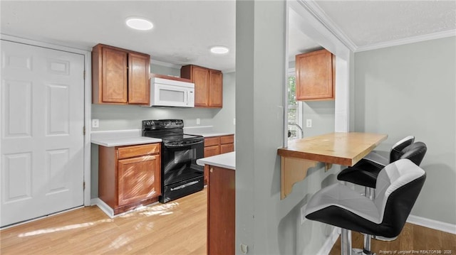 kitchen featuring brown cabinetry, white microwave, ornamental molding, black electric range oven, and light countertops