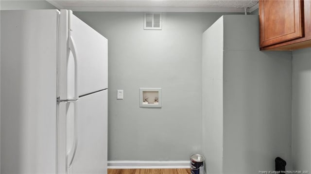 clothes washing area with hookup for a washing machine, cabinet space, visible vents, light wood-style flooring, and baseboards