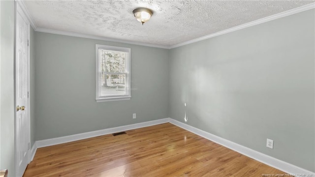 spare room featuring baseboards, visible vents, wood finished floors, crown molding, and a textured ceiling