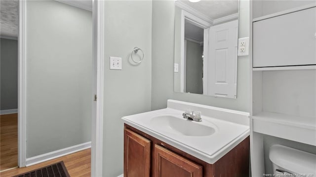 bathroom with baseboards, vanity, toilet, and wood finished floors