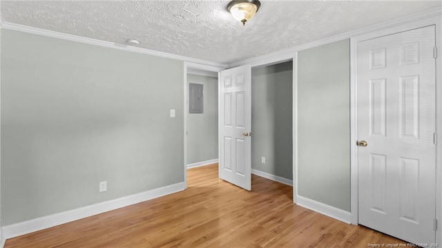 unfurnished bedroom featuring electric panel, baseboards, a textured ceiling, light wood-type flooring, and a closet