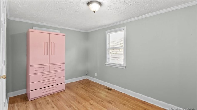 unfurnished bedroom featuring visible vents, ornamental molding, light wood-style flooring, and baseboards