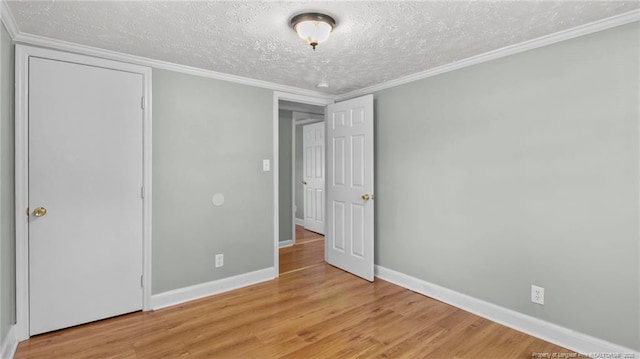 unfurnished bedroom with baseboards, light wood-style flooring, ornamental molding, and a textured ceiling