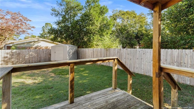 wooden deck with a yard, a shed, a fenced backyard, and an outbuilding