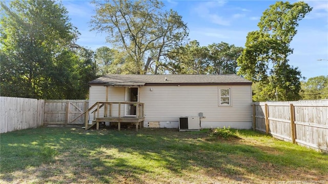 back of house with a fenced backyard, a yard, and central AC