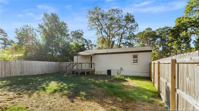 back of house with a fenced backyard, central AC, and a yard