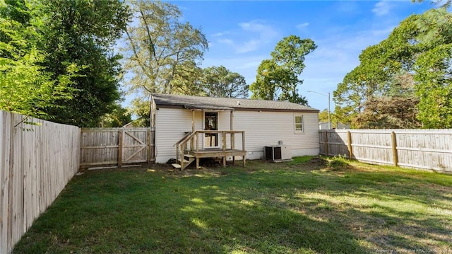 rear view of property with a yard, central AC unit, a fenced backyard, and a gate