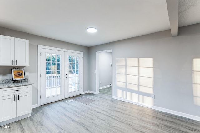 doorway with beamed ceiling, french doors, and light wood-type flooring