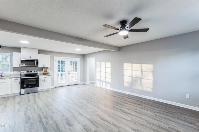 kitchen featuring a textured ceiling, stainless steel appliances, white cabinetry, and french doors