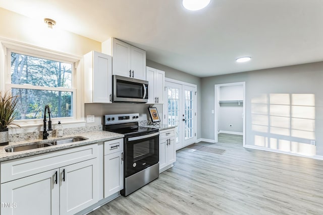 kitchen with light hardwood / wood-style floors, sink, stainless steel appliances, white cabinets, and light stone counters