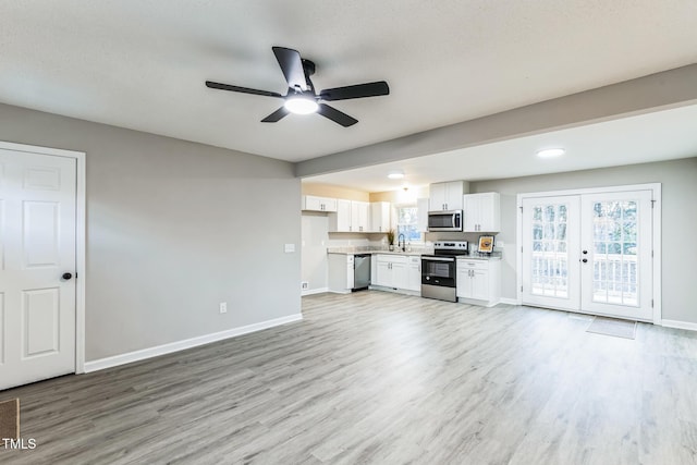 unfurnished living room with ceiling fan, sink, light hardwood / wood-style flooring, and french doors