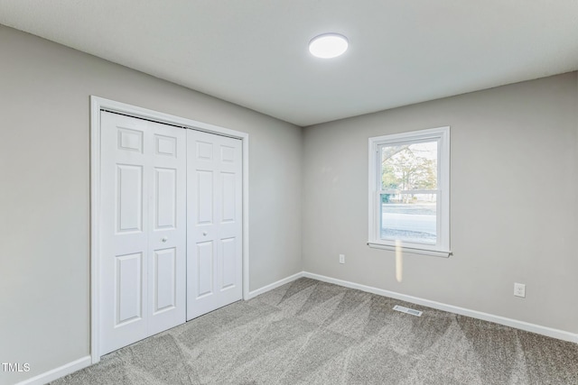 unfurnished bedroom with light carpet and a closet