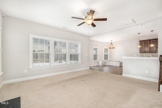 unfurnished living room with ceiling fan with notable chandelier and carpet