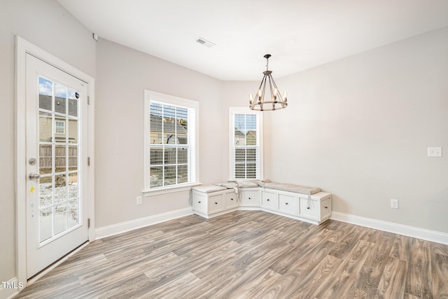 unfurnished dining area with a chandelier and light hardwood / wood-style flooring