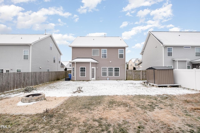 rear view of property featuring a storage unit and a fire pit