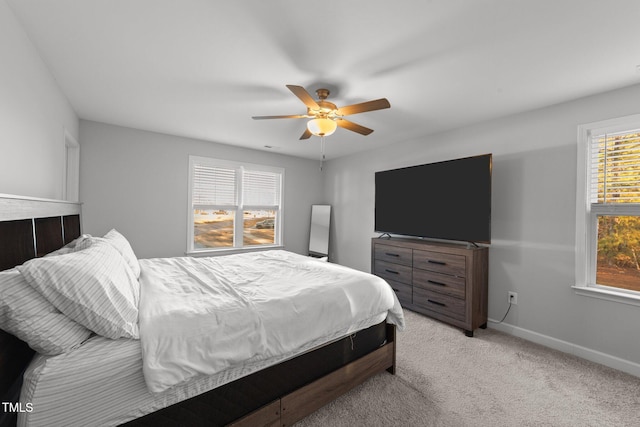 bedroom with ceiling fan, light colored carpet, and multiple windows