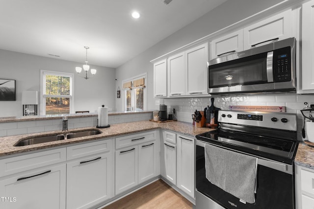 kitchen with white cabinets, sink, an inviting chandelier, and stainless steel appliances