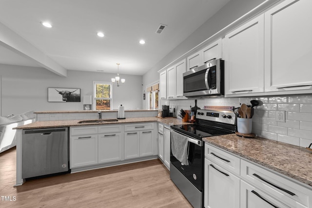 kitchen featuring hanging light fixtures, white cabinets, kitchen peninsula, and appliances with stainless steel finishes