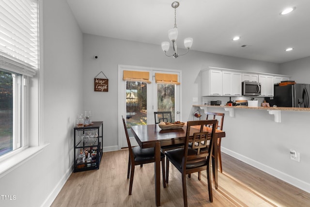 dining space featuring light wood-type flooring, plenty of natural light, and an inviting chandelier