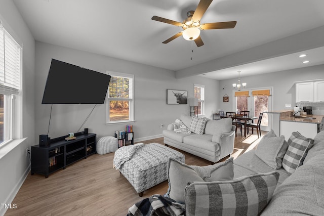 living room featuring ceiling fan with notable chandelier, plenty of natural light, light hardwood / wood-style flooring, and sink