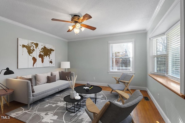 living room with crown molding, ceiling fan, hardwood / wood-style flooring, and a textured ceiling