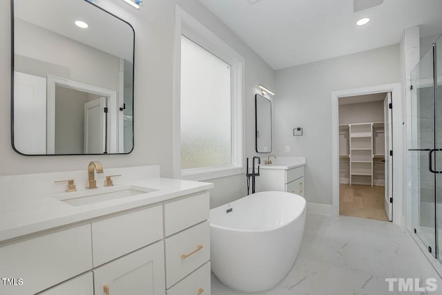 bathroom featuring a walk in closet, marble finish floor, a sink, a shower stall, and a freestanding tub