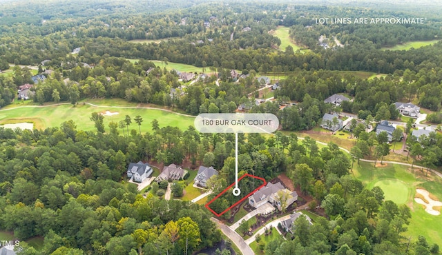 drone / aerial view featuring view of golf course and a view of trees