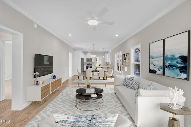 living room featuring light hardwood / wood-style flooring, ceiling fan, and ornamental molding