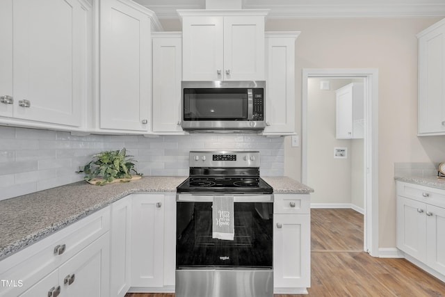 kitchen with white cabinetry, ornamental molding, backsplash, stainless steel appliances, and light stone counters