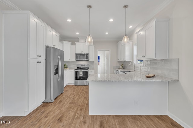 kitchen with appliances with stainless steel finishes, decorative light fixtures, white cabinetry, sink, and kitchen peninsula