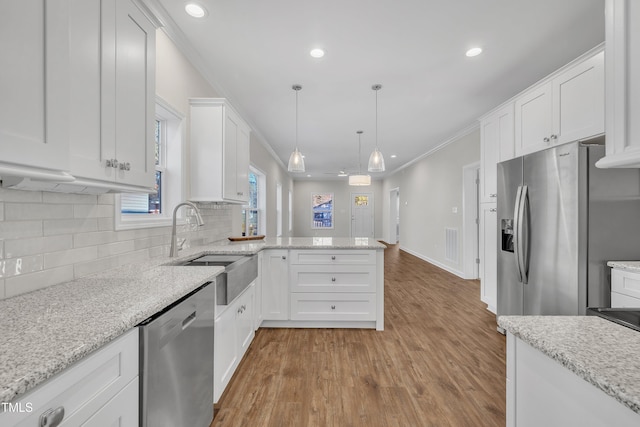 kitchen featuring crown molding, hanging light fixtures, white cabinets, kitchen peninsula, and stainless steel appliances