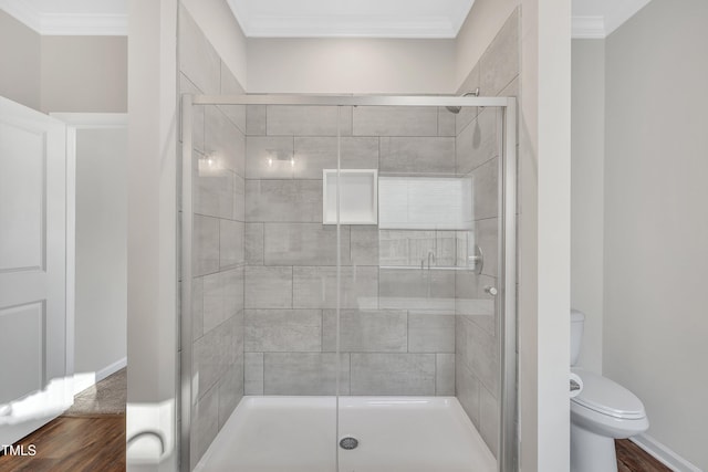 bathroom with hardwood / wood-style floors, toilet, ornamental molding, and an enclosed shower