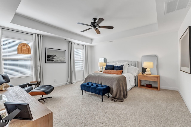 bedroom with ceiling fan, a tray ceiling, and light carpet