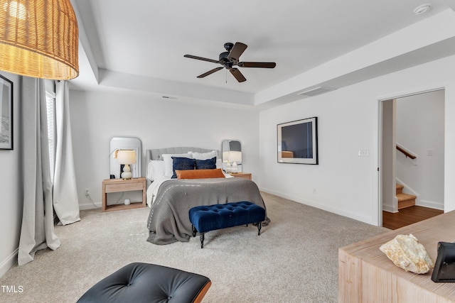 bedroom with ceiling fan, carpet, and a tray ceiling