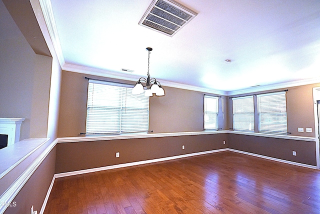 spare room with an inviting chandelier, ornamental molding, and plenty of natural light