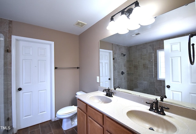 bathroom with toilet, tiled shower, and vanity