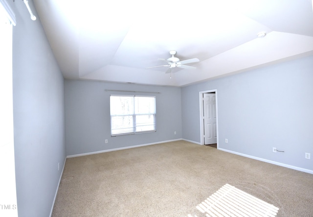 carpeted spare room featuring ceiling fan and a tray ceiling